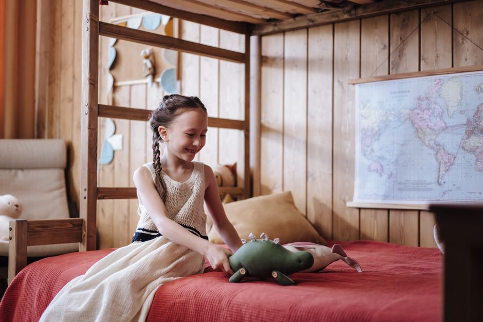 Minecraft posters: een speelse twist voor kinderkamers dit najaar - Een jong meisje speelt vrolijk met haar speelgoeddinosaurus op een bed, in een warm ingericht kamer. Minecraft posters: een speelse twist voor kinderkamers dit najaar - Een jong meisje speelt vrolijk met haar speelgoeddinosaurus op een bed, in een warm ingericht kamer.